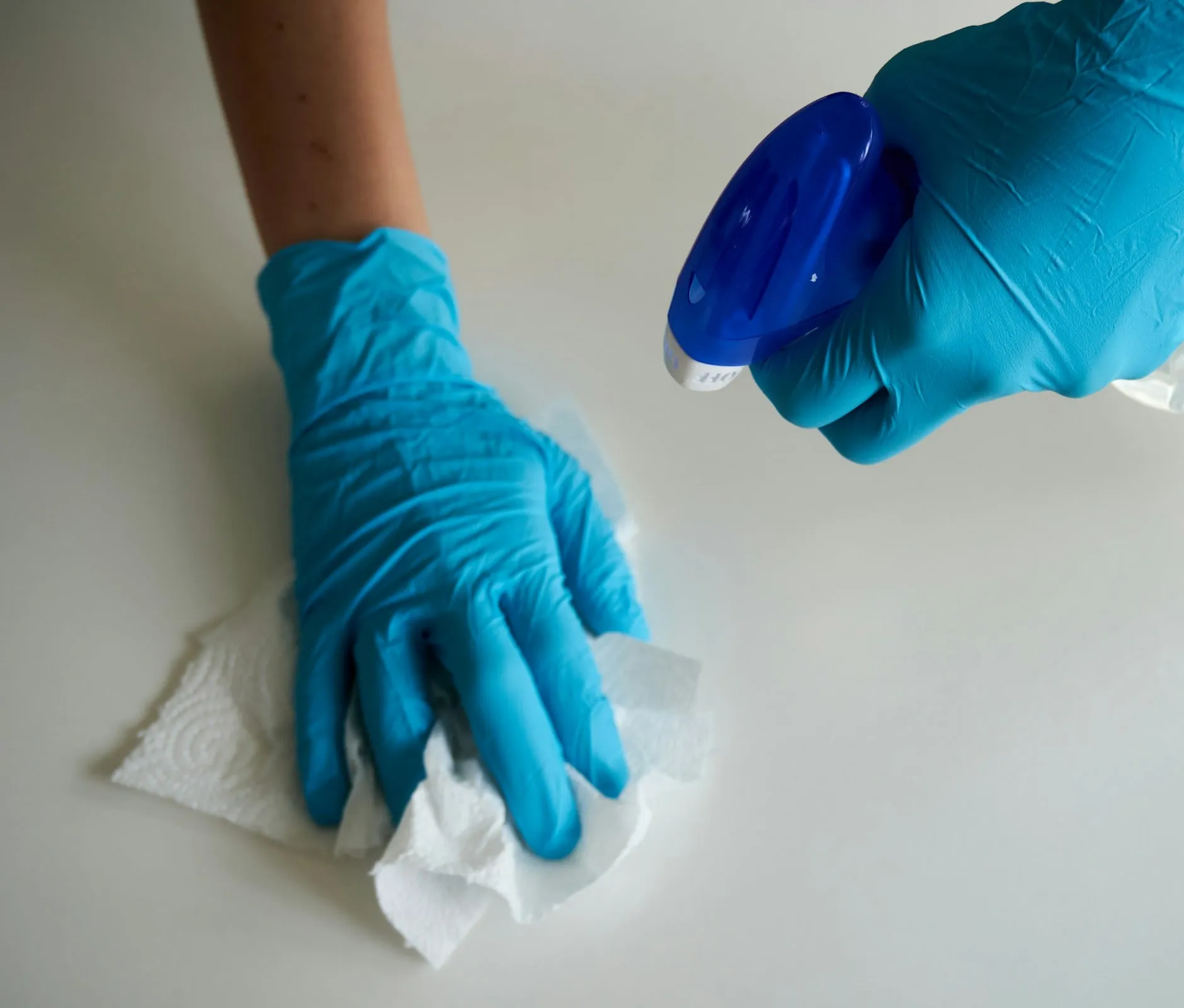 Profissional de limpeza usando luvas e produto de limpeza em uma superfície